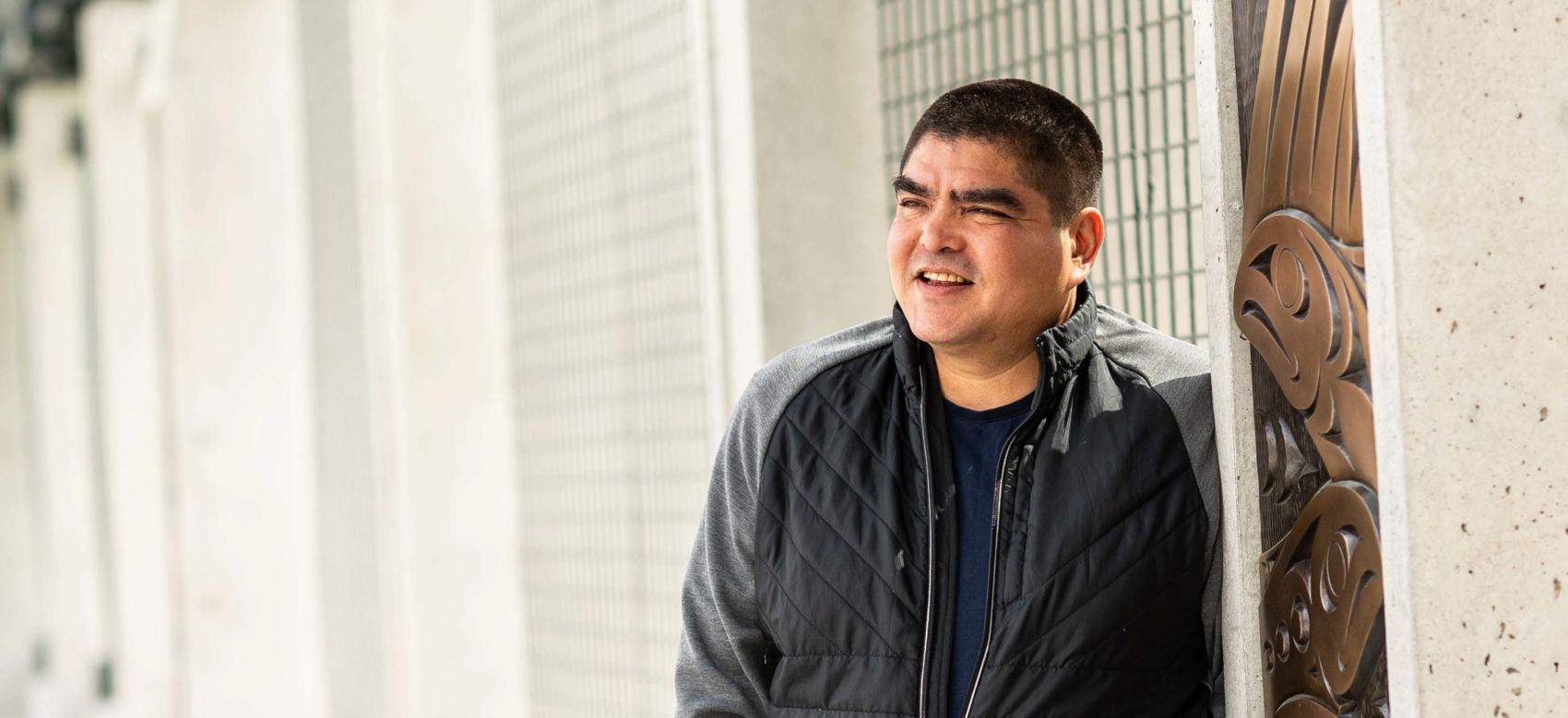 Musqueam artist Brett Sparrow with his artwork on the UBC Vancouver campus
