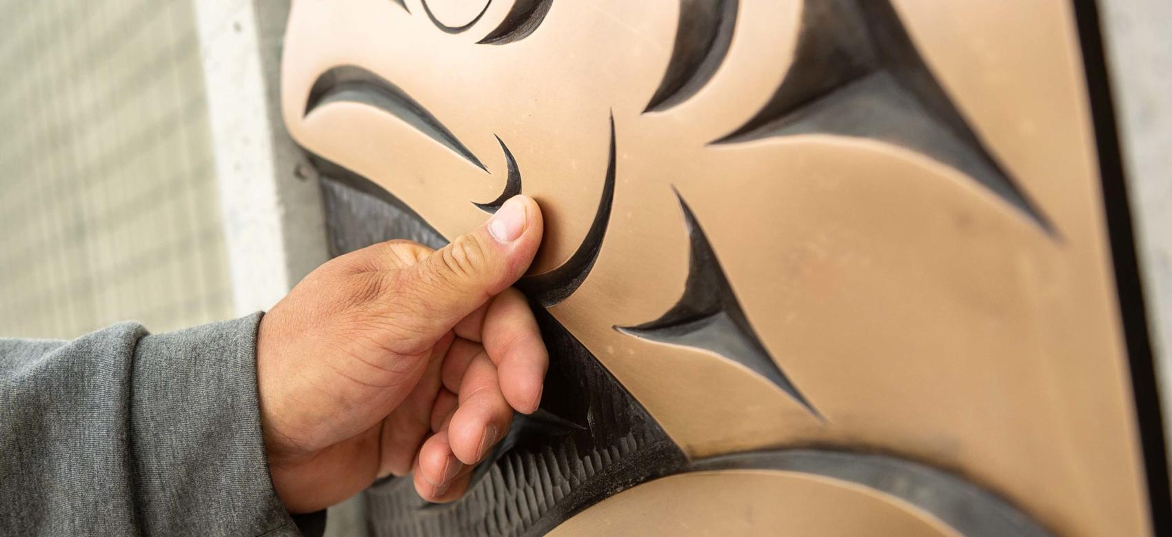 Musqueam artist Brett Sparrow with the bronze cast of his artwork on the UBC Vancouver campus