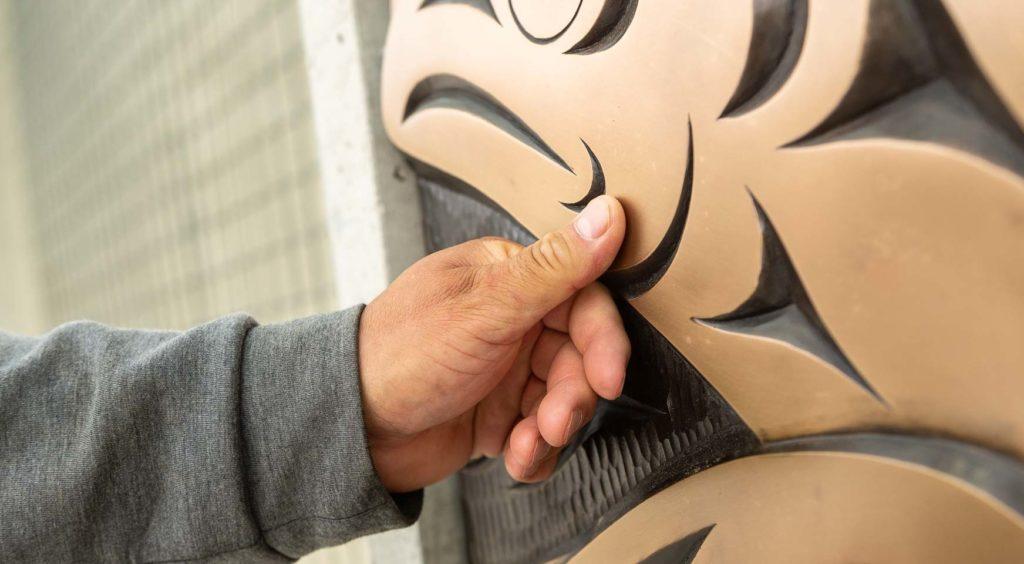 Musqueam artist Brent Sparrow with the bronze cast of his artwork on the UBC Vancouver campus