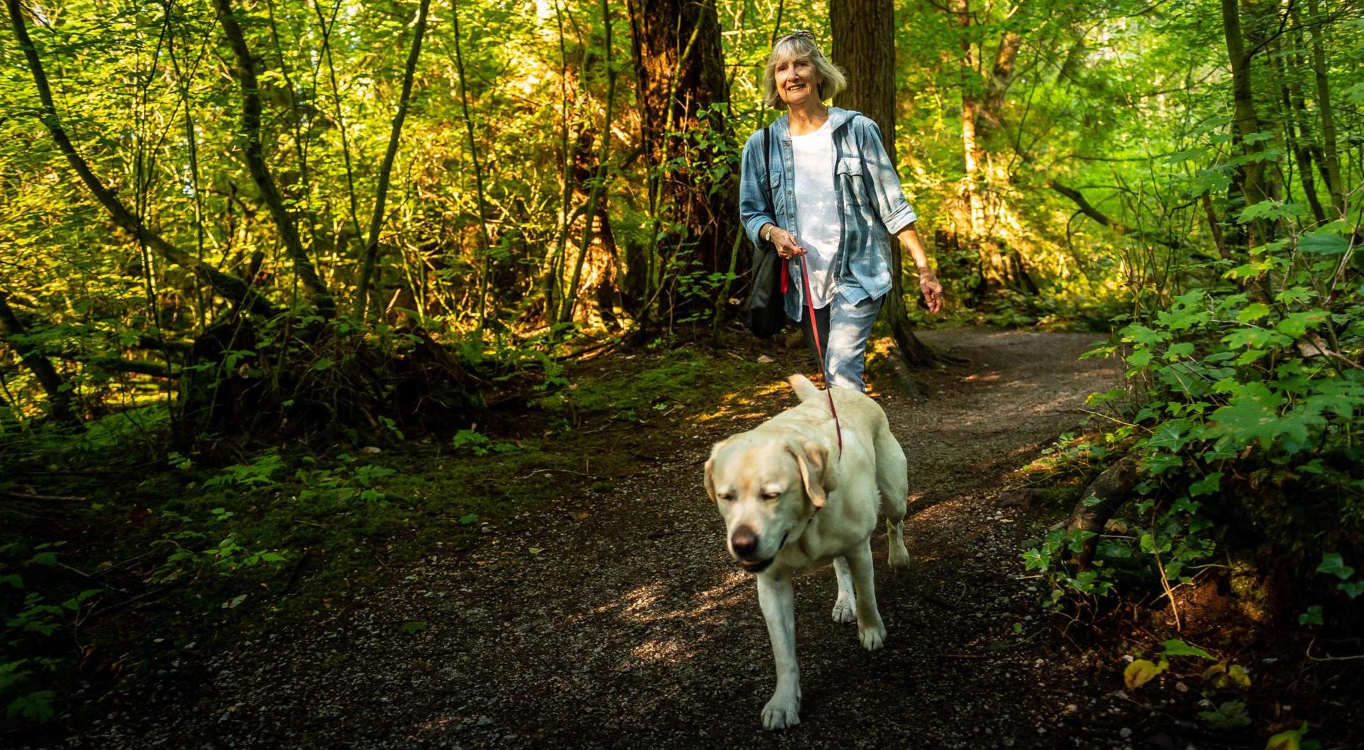 An active, older adult walks her dog in the park