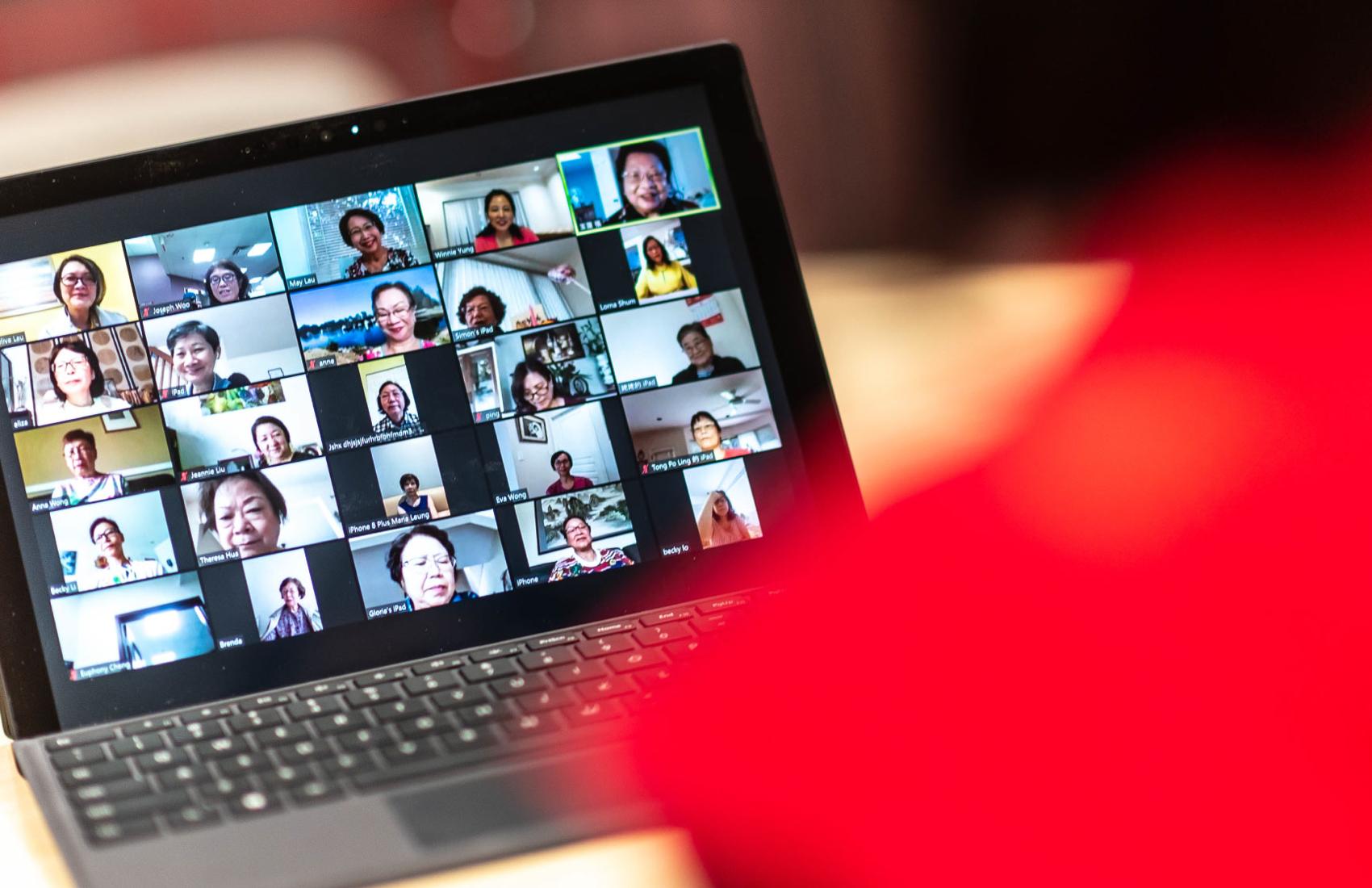 A laptop screen shows a video conference conversation on Zoom between 25 senior adults