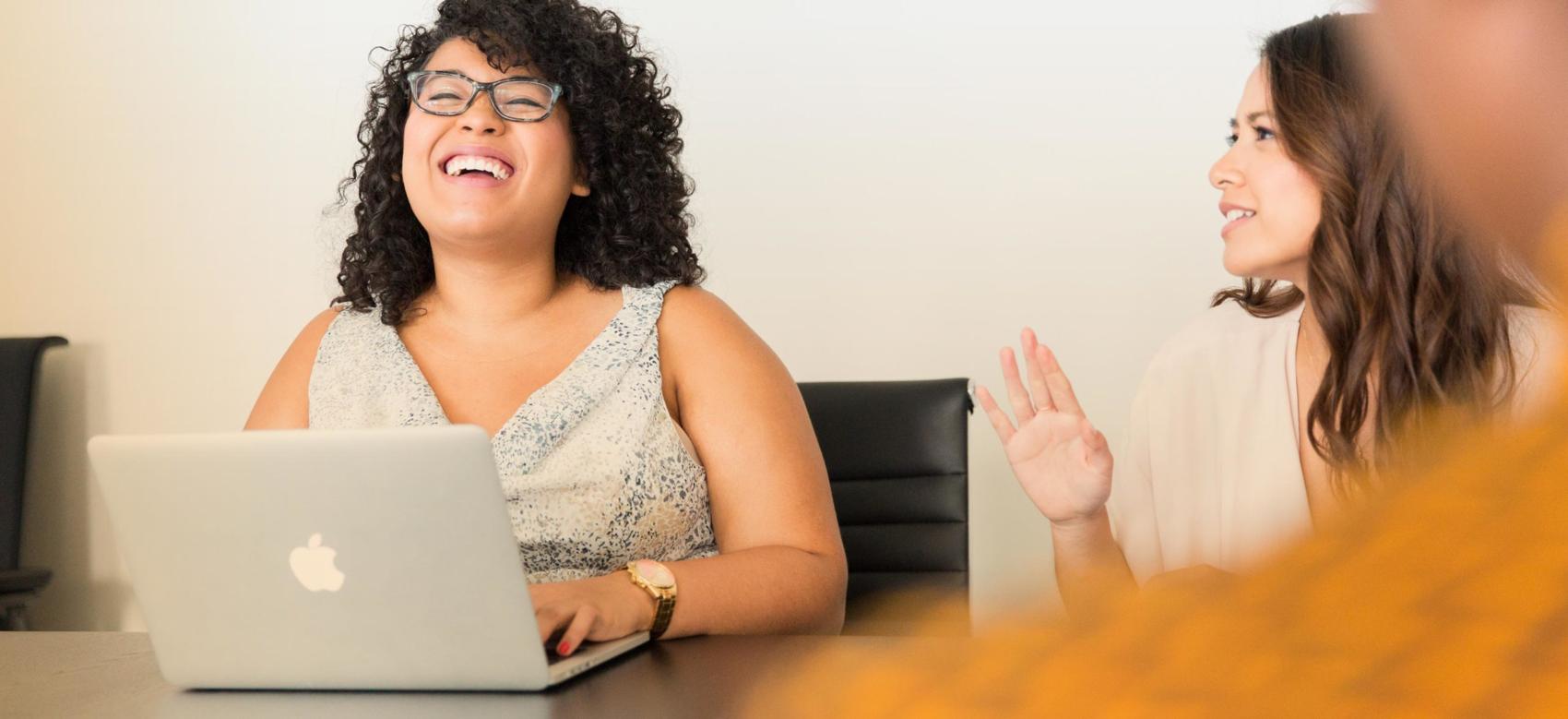 Two women laugh together at an office