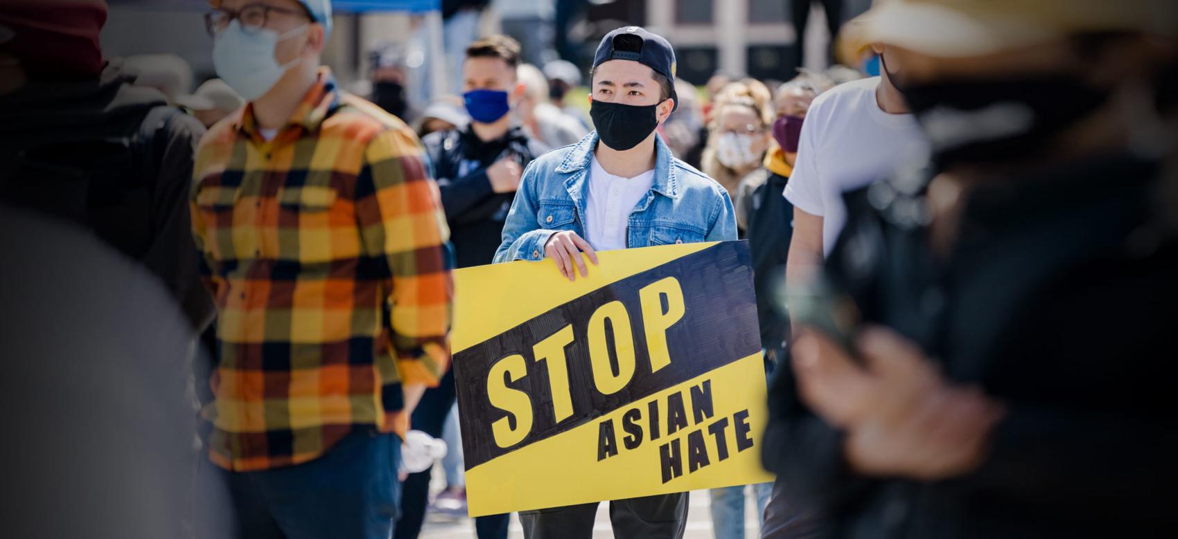 A man holds a #StopAsianHate sign at a large rally