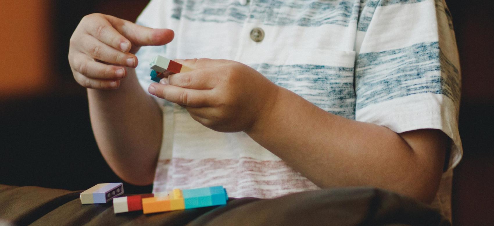 A young child with autism plays with colourful building blocks