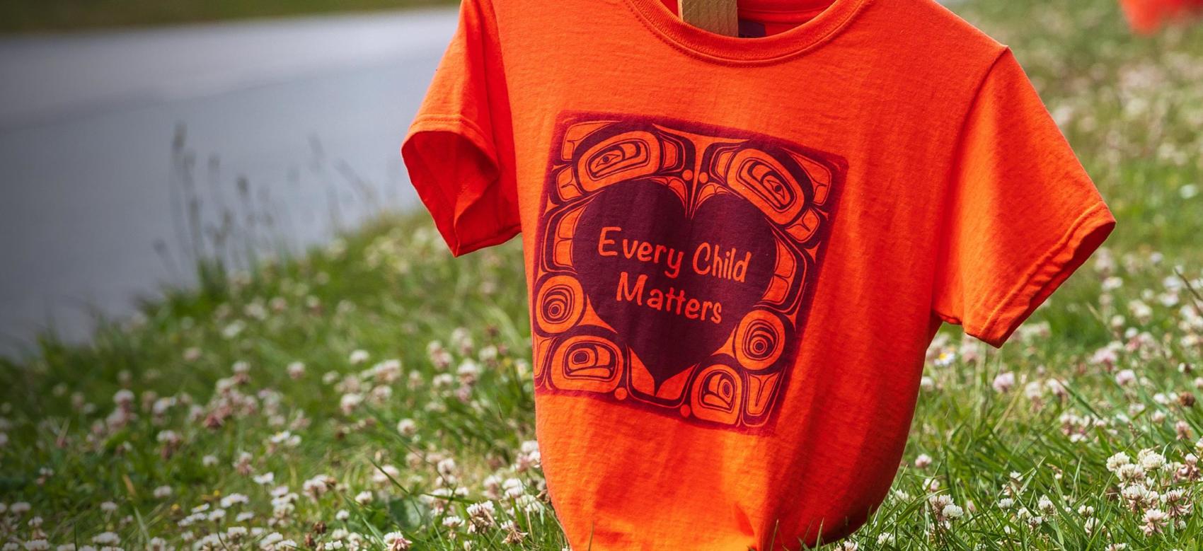 Orange shirts with the phrase "Every Child Matters" printed on them line Marine Drive in Vancouver as a memorial for the Indigenous children who were sent to residential schools in Canada.