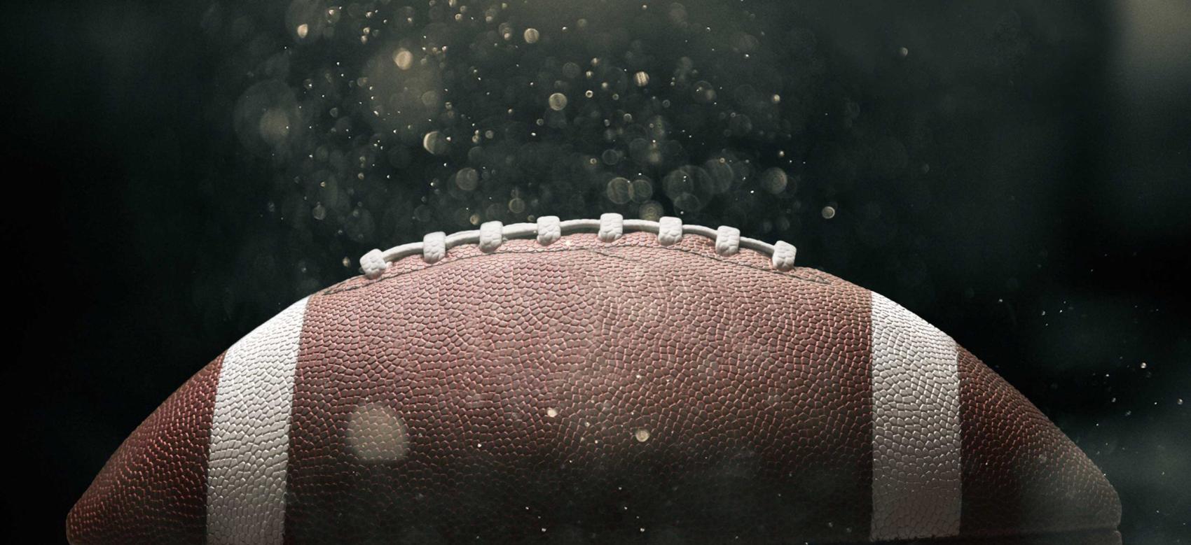 Photo of a football on a dark background with moisture surrounding it