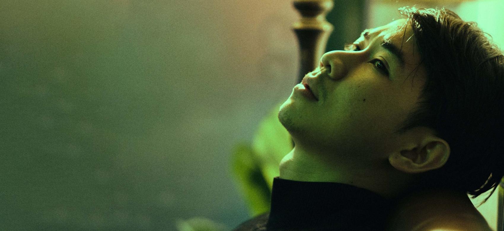 Young man in a dark room with his head back on a sofa