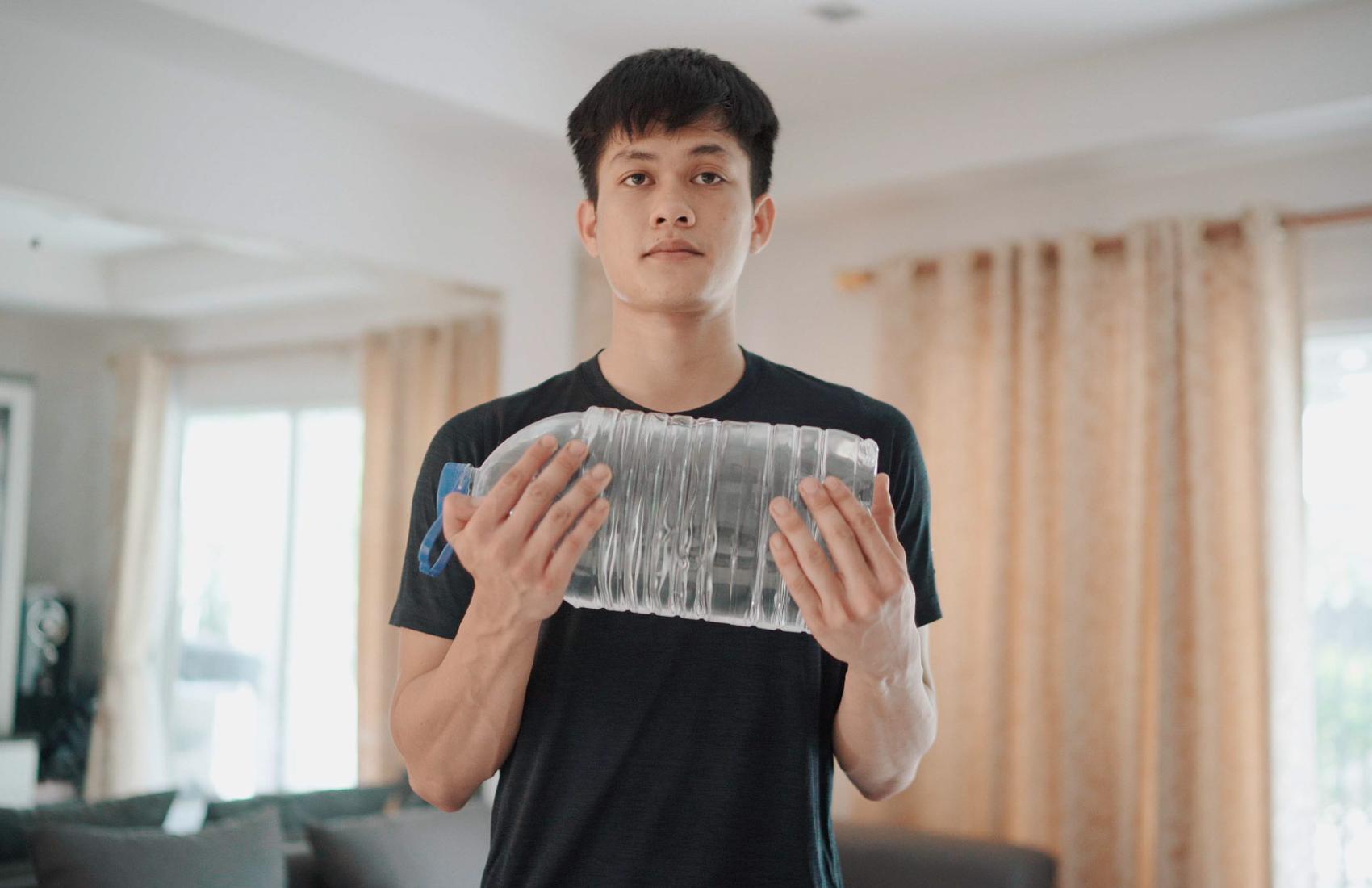 Person doing arm curls with a large water bottle in the living room