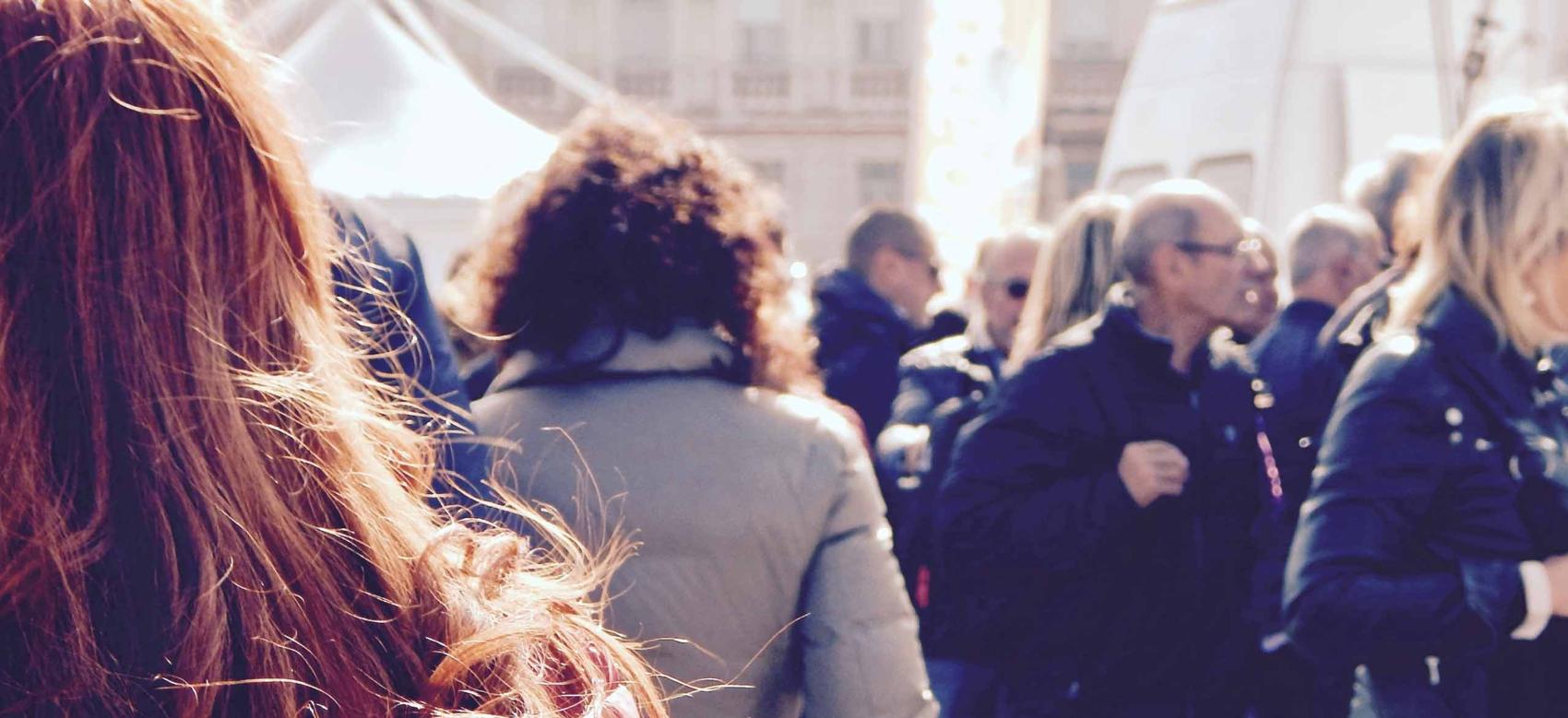 People walking outside in a crowded public area.