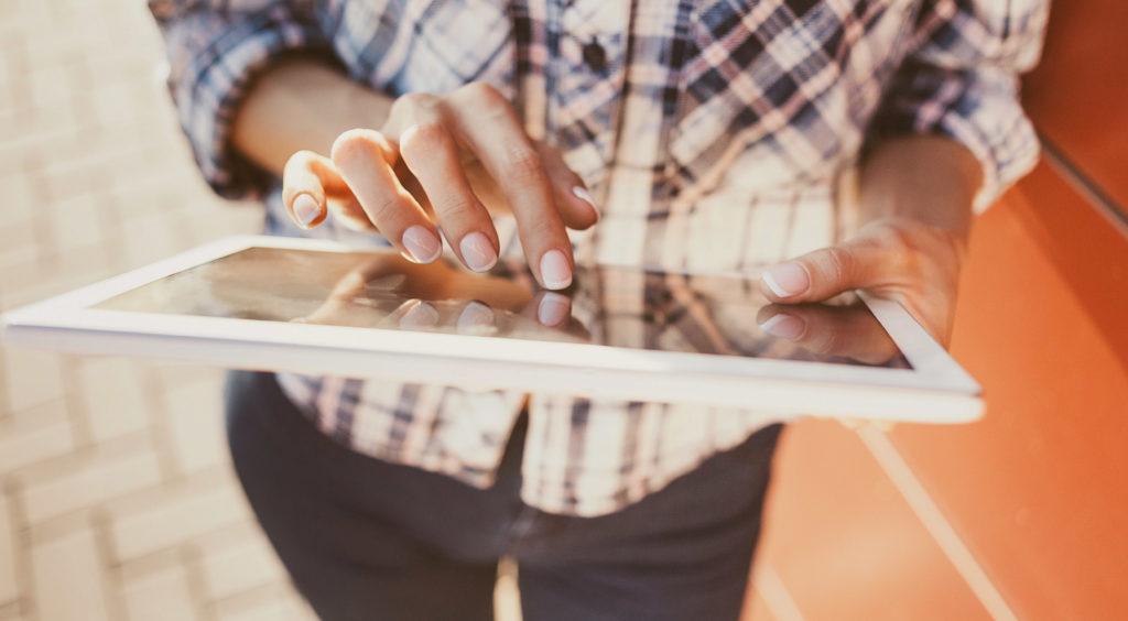 A photo of a young woman's hands using social media on an tablet