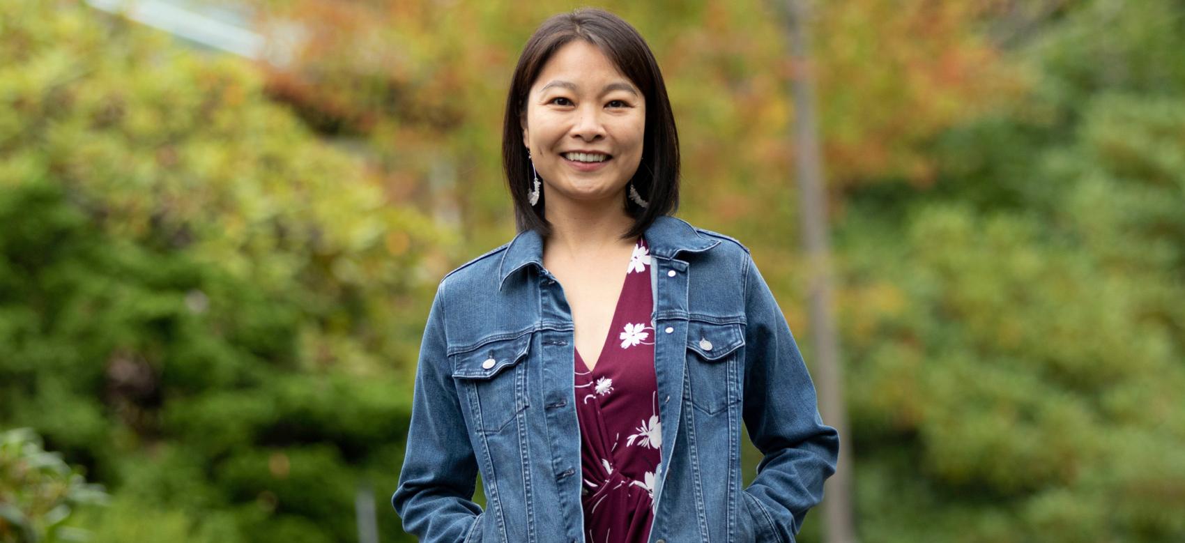 Photo of Dr. Nancy Sin standing in a field surrounded by greenery