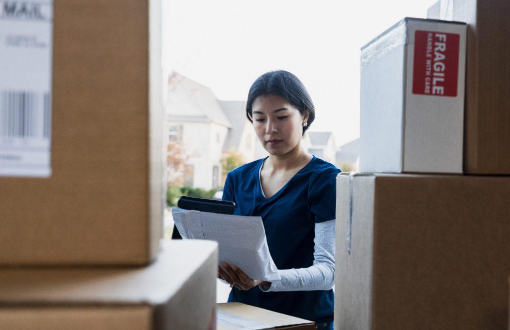 A delivery worker checking boxes at the back of a van