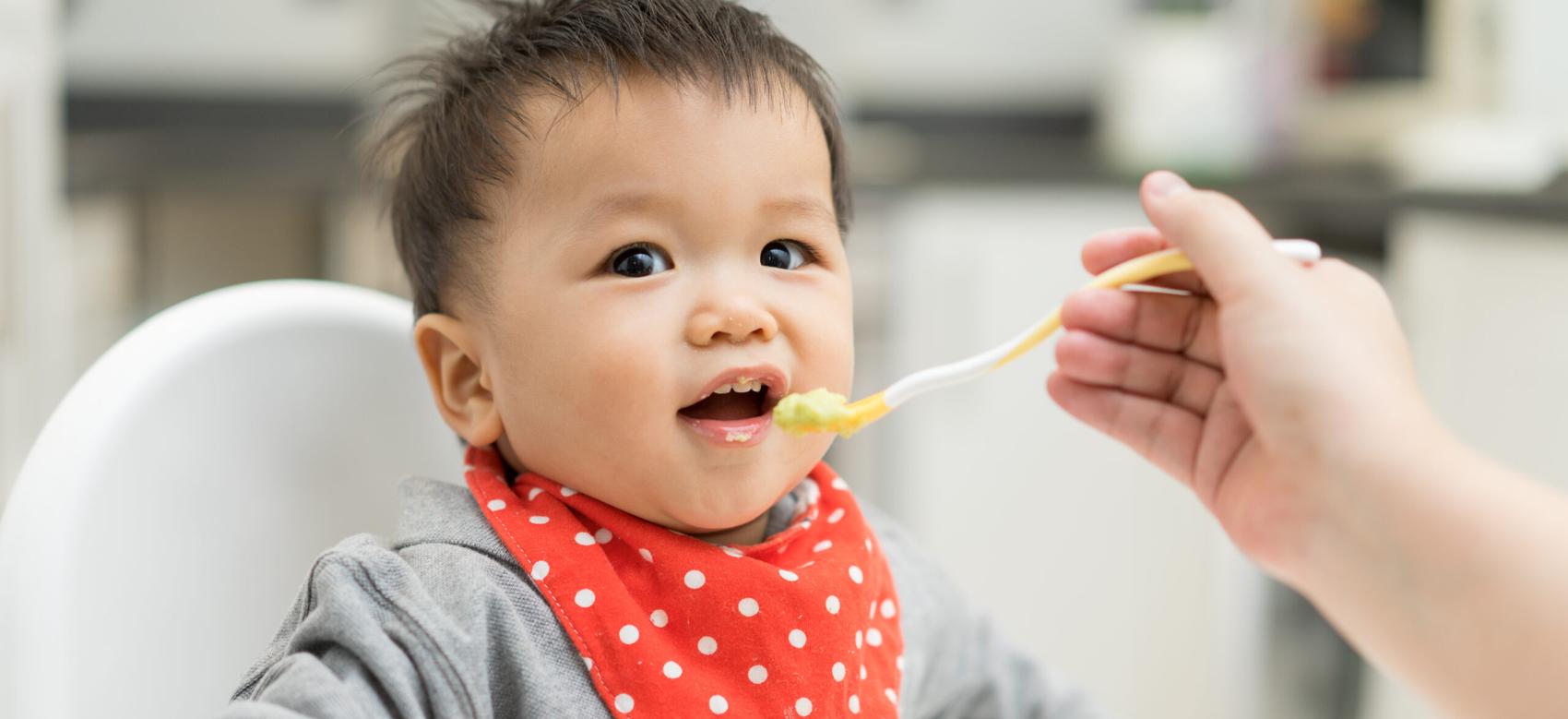 A baby eating blended food on a high chair.