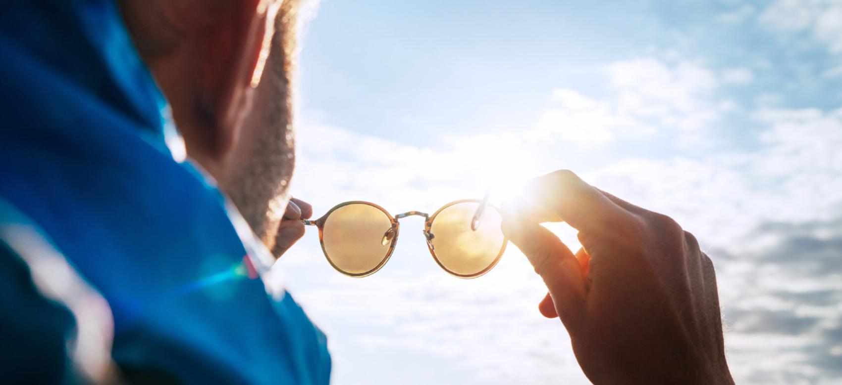 A person looking at the sun through their sunglasses.