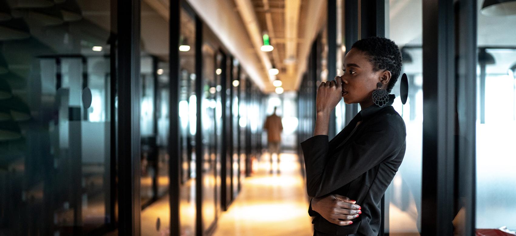 Young black business woman looking away in contemplation at work