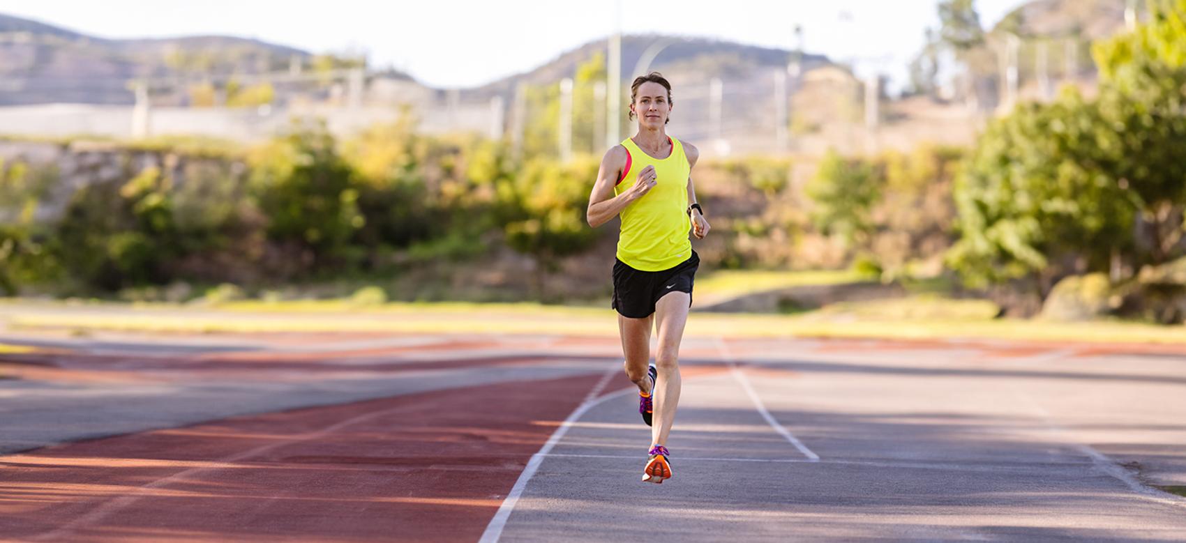 Malindi Elmore in a yellow tank top and black shorts running on a track. Elmore speaks on gender equity in sports.