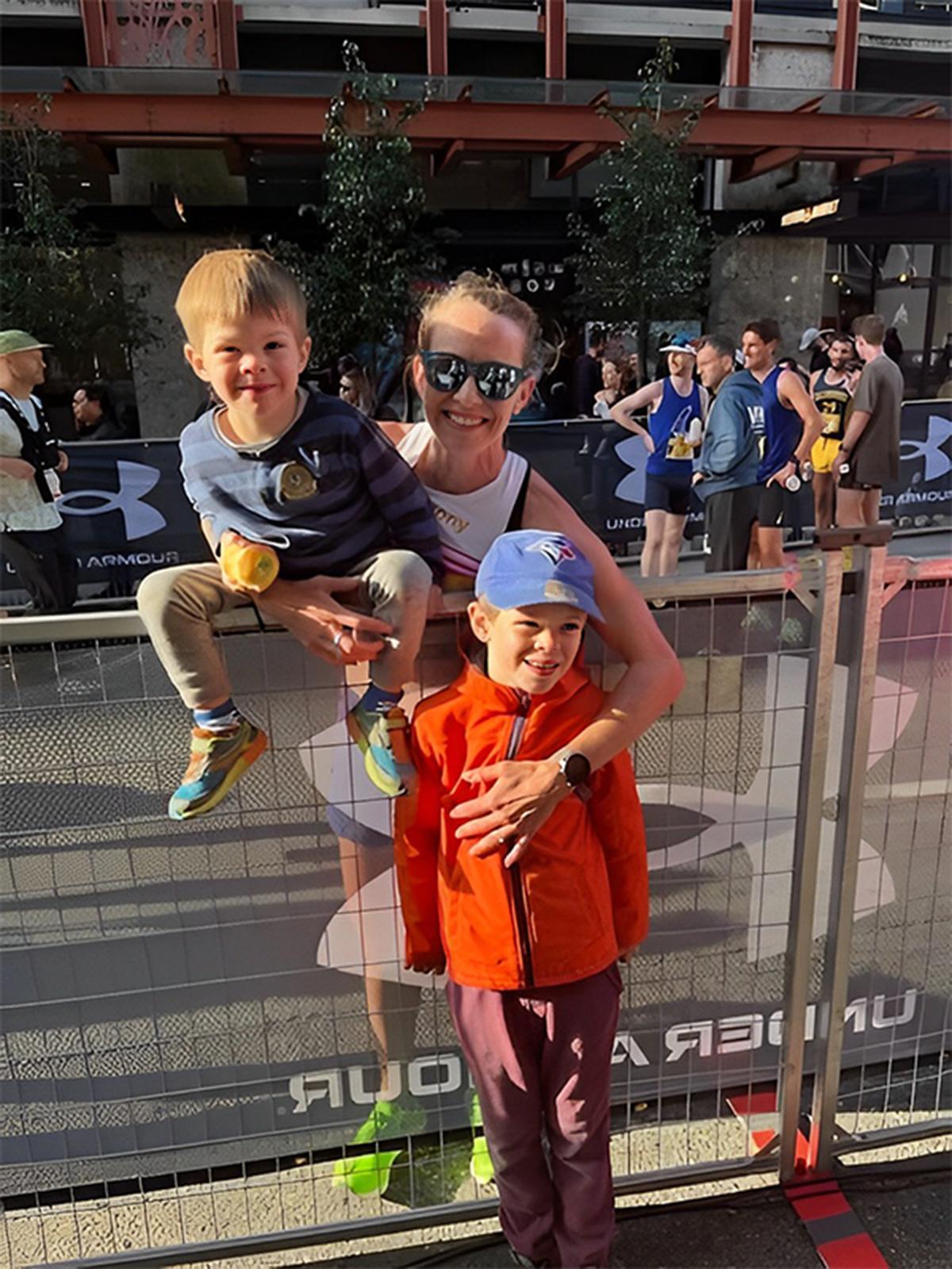 Canadian marathon runner Malindi Elmore holds her two children on a fence at a race site.