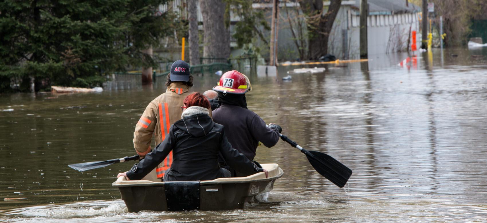 Emergency workers paddle two civilians in a small rowboat in a flooded neighbourhood on Cousineau St., in the Ahuntsic-Cartierville borough, Montreal.